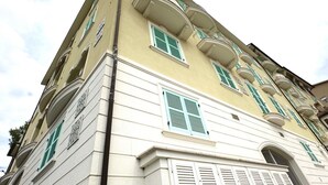 A multi-story building with balconies, large windows with shutters, and a corner entrance. - N219 - Numana, delightful two-room apartment in the center (Numana)