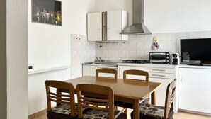 A modern kitchen with white cabinets, a dining table with chairs, a stove, a microwave, and a hanging light fixture. - N219 - Numana, delightful two-room apartment in the center (Numana)