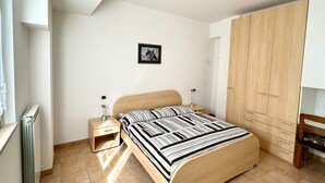 A bedroom with a bed, bedside tables, a wardrobe, and a framed picture on the wall. - N219 - Numana, delightful two-room apartment in the center (Numana)