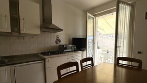 A kitchen with a stove, microwave, and cabinets, a dining table with chairs, and a sliding glass door leading to an outdoor area. - N219 - Numana, delightful two-room apartment in the center (Numana)