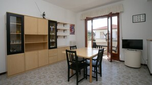 Une pièce comprenant une table à manger, des chaises, un téléviseur, un meuble et un radiateur.