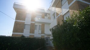 Un immeuble à plusieurs étages, doté d’un toit plat, d’une entrée bien visible et surplombant un ciel dégagé.