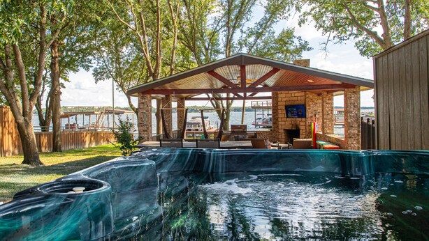Ein Whirlpoolbereich mit Holzterrasse, Steinwänden und Seeblick.