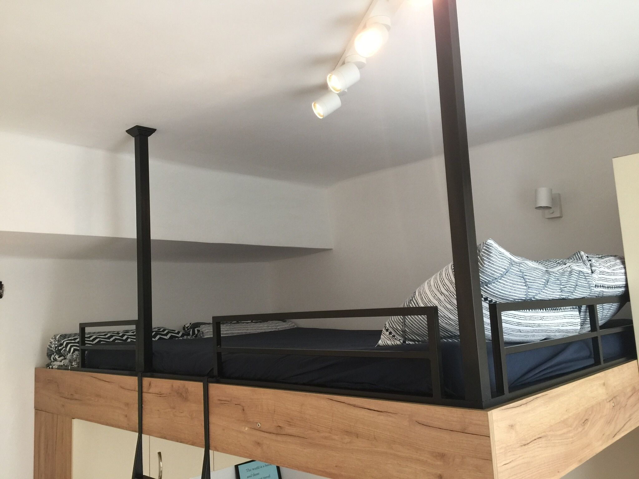 Una cama litera con estructura de madera y baranda de metal negro.