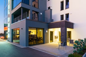 A modern hotel with a glass facade, outdoor seating area, and a visible restaurant inside. - Hotel Duda Boardingroom (Reichertshofen)