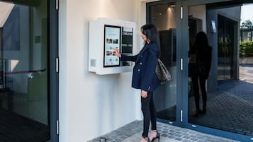 Une femme utilisant un terminal d’enregistrement numérique situé à l’entrée d’un hôtel.