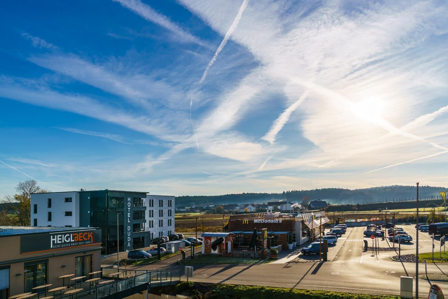 A hotel with a modern design, a McDonald's restaurant, and a parking lot.