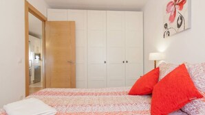 Ein Schlafzimmer mit einem Bett, einer Holztür, einem weißen Kleiderschrank und einem Bild an der Wand.