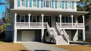 A two-story house with a covered porch, a staircase, and a garage. - Stunning 5 Bedroom Home, Short Walk to Beach, Includes 2 Golf Carts, 809 Bonito Road 809 Bonito Drive (Fripp Island)