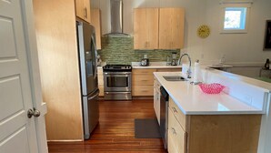 A modern kitchen with wooden cabinets, stainless steel appliances, and a large island with a sink. - Stunning 5 Bedroom Home, Short Walk to Beach, Includes 2 Golf Carts, 809 Bonito Road 809 Bonito Drive (Fripp Island)