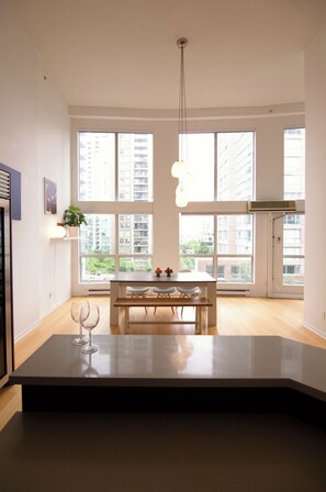A modern kitchen with a dining area, large windows, and a hanging light fixture. - Rare luxury Downtown Vancouver loft/sleeps 8/2 bedroom + 2 bath/1500sf + parking (Vancouver)