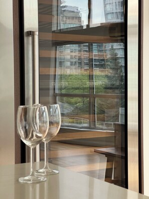 Two empty wine glasses on a reflective surface, a window with a view of buildings and trees, and a partial view of a wooden structure. - Rare luxury Downtown Vancouver loft/sleeps 8/2 bedroom + 2 bath/1500sf + parking (Vancouver)