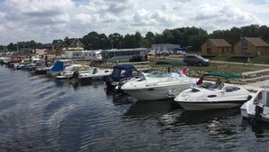 Un port de plaisance où sont amarrés différents types de bateaux, avec un autobus et des camping-cars en arrière-plan.