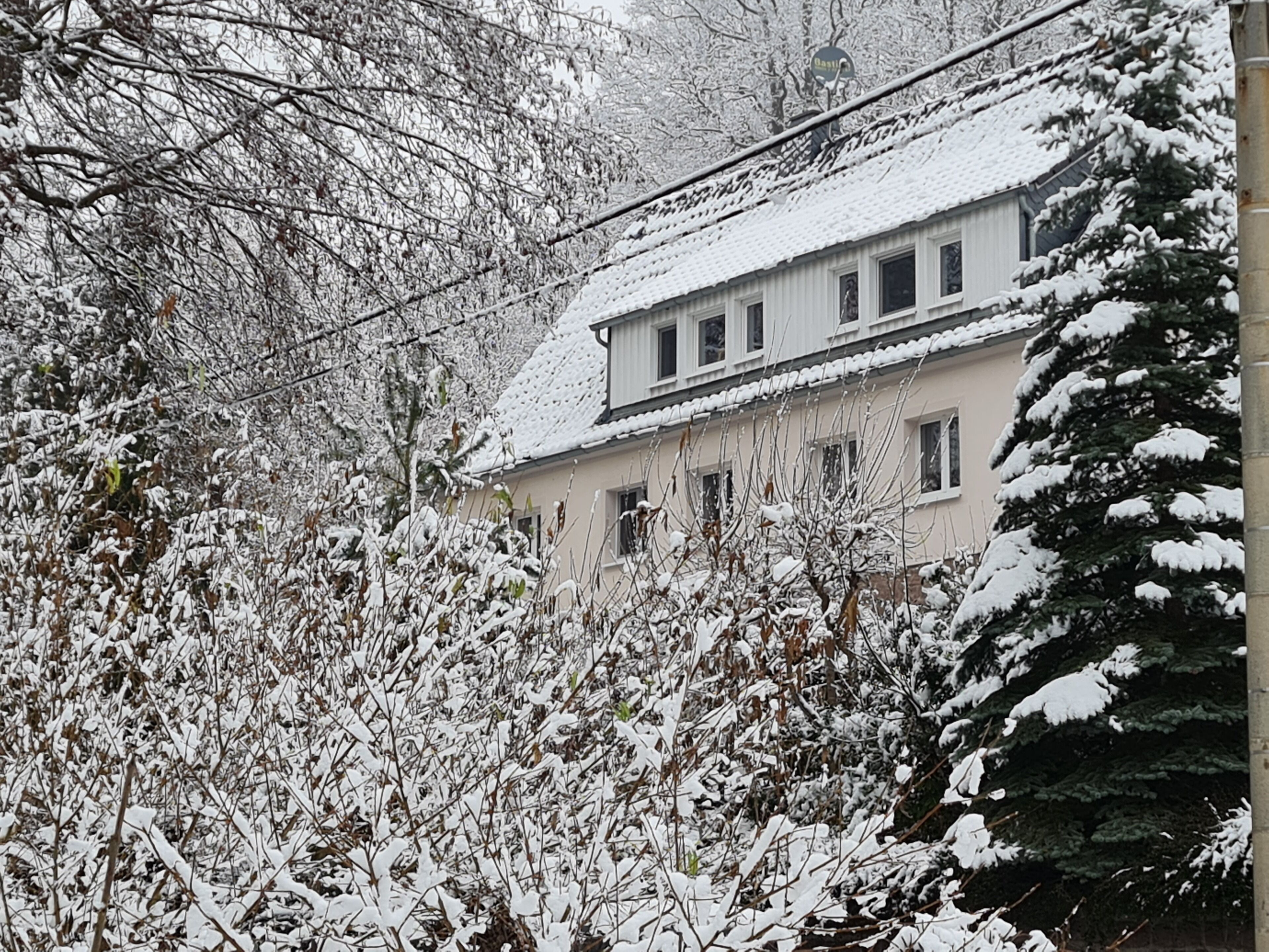 Un edifici de dues plantes amb un teulat cobert de neu i finestres.