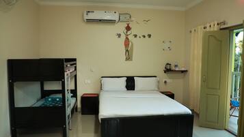 A bedroom with a bunk bed, a single bed, an air conditioner, a wall decoration, a door, and a small shelf.