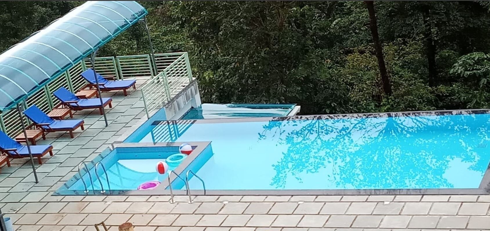 Piscina con sillones de descanso y una zona de estar techada.