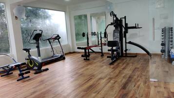 A gym with exercise equipment, wooden flooring, and large windows.
