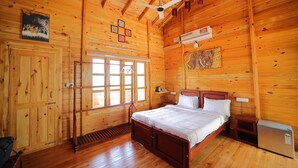 Un dormitorio de cabaña de madera con cama, escritorio, silla, ventana y ventilador de techo.