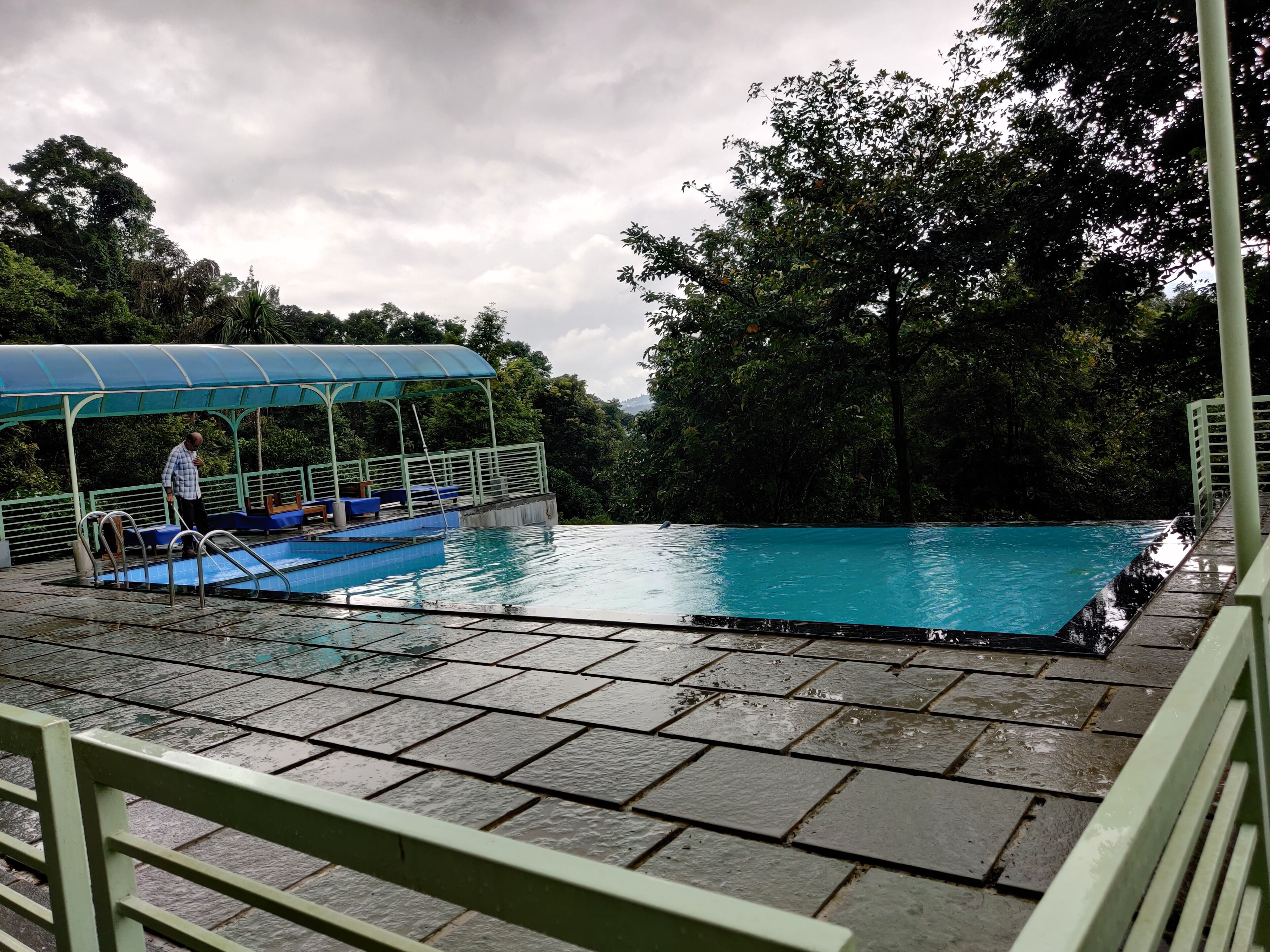 Una piscina amb una zona de seients coberta i una persona de peu al costat.