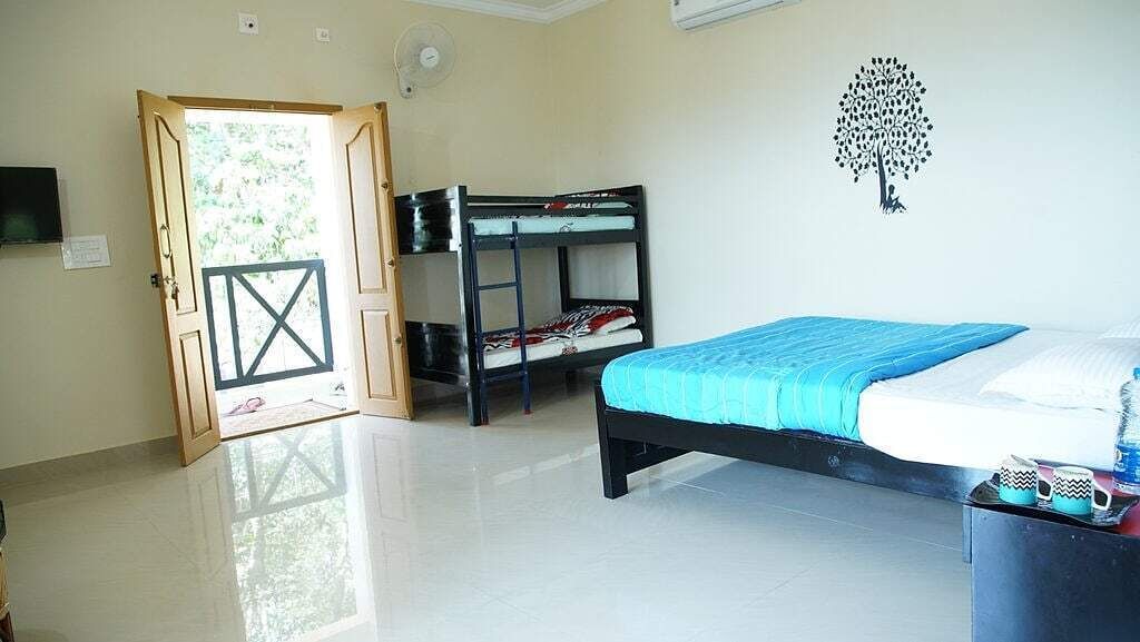 A bedroom with a bunk bed, a single bed, a door leading outside, and a wall decoration.