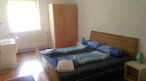 Ein Schlafzimmer mit einem Bett, einem Schreibtisch, einem Kleiderschrank und einer Heizung.