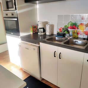 Una cucina accessoriata con forno a microonde, forno, macchina del caffè e lavello.
