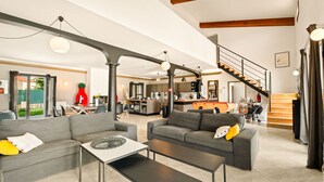 A spacious living area with grey sofas, a coffee table, and a staircase leading to a kitchen. - Casa Nova Maison d'hotes (Coggia)