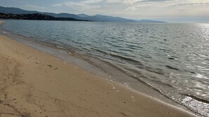 A beach with clear water, a sandy shore, and distant mountains under a partly cloudy sky. - Casa Nova Maison d'hotes (Coggia)