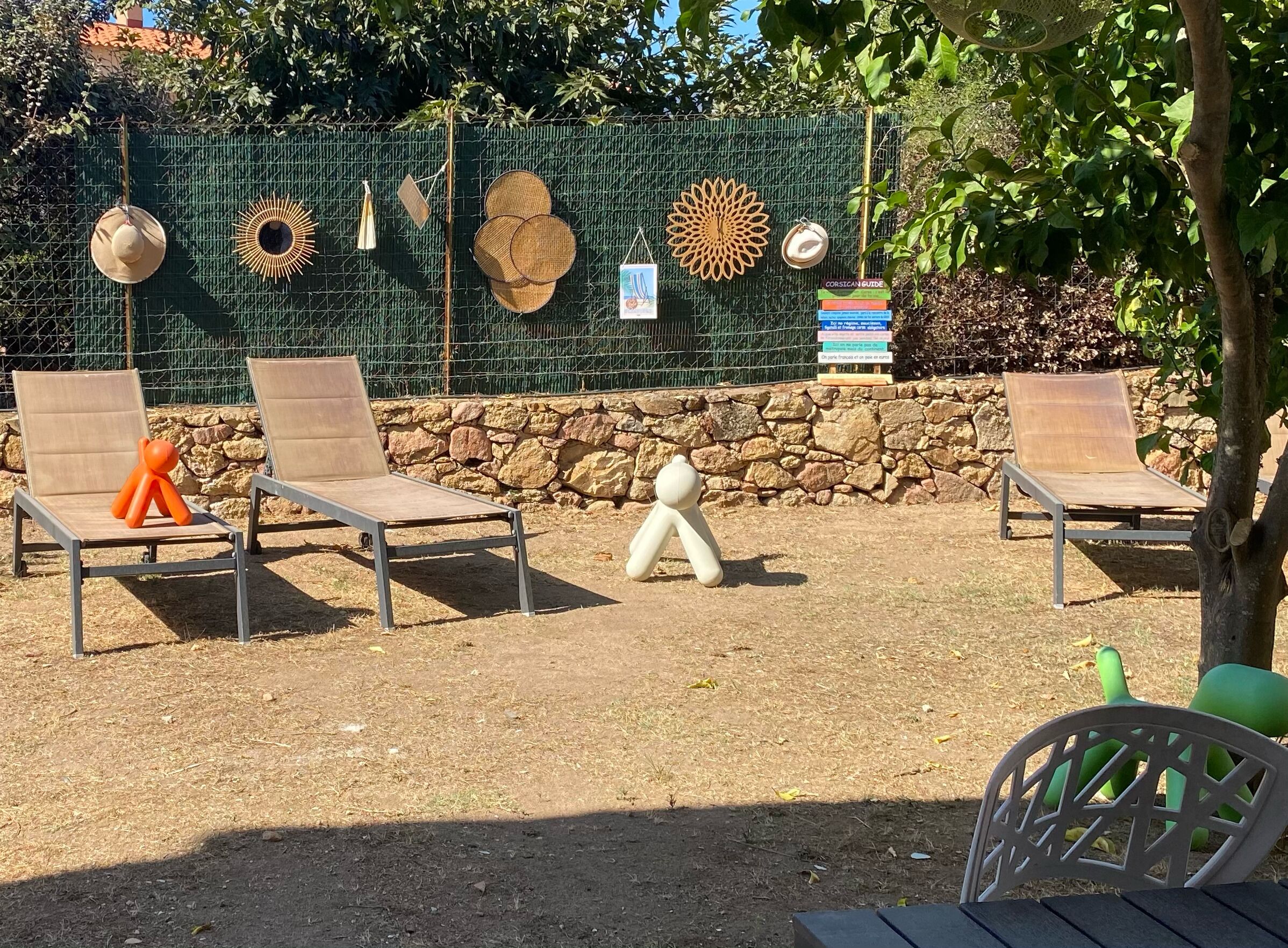 Un'area patio con due poltrone, un muro decorativo con diversi oggetti e un muro in pietra sullo sfondo.