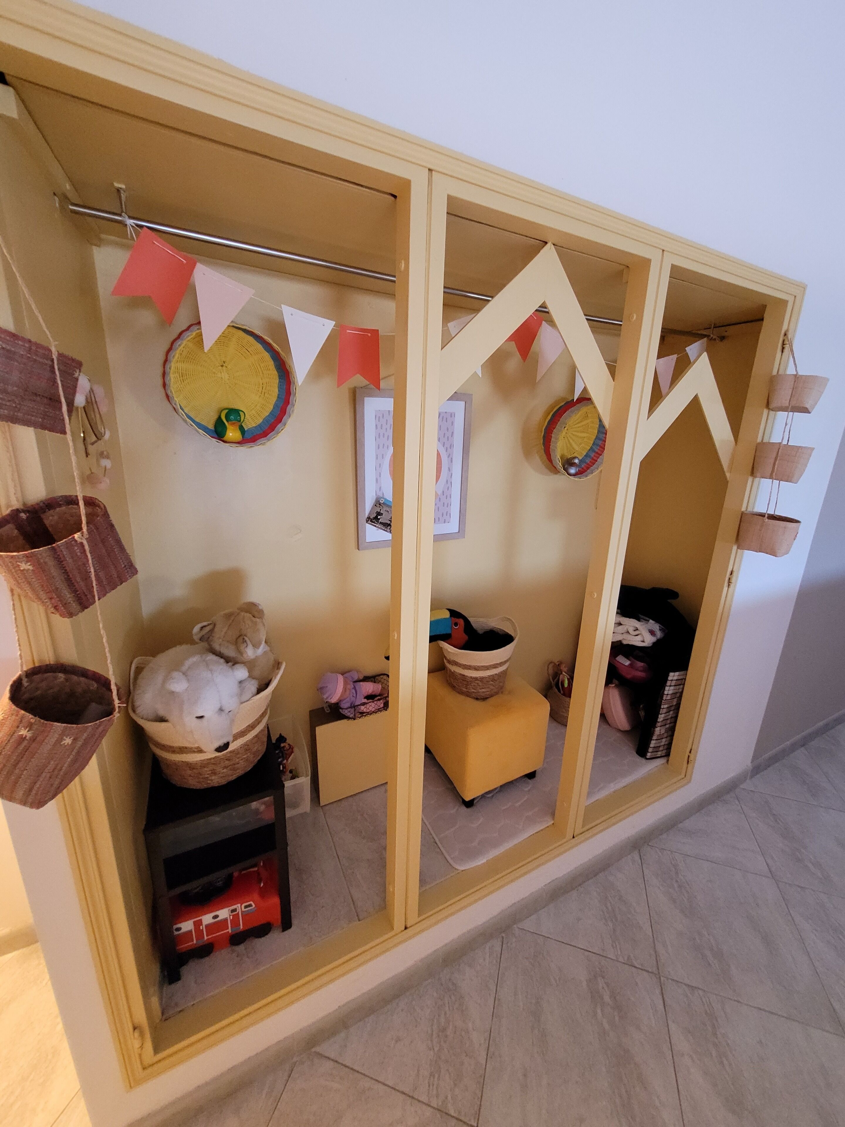 Una habitación con un armario amarillo, una mesita pequeña y una cesta colgante.