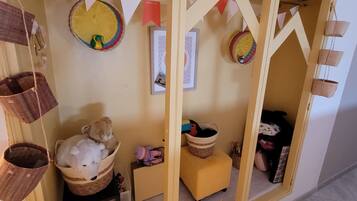 Una habitación con un armario amarillo, una mesita pequeña y una cesta colgante.