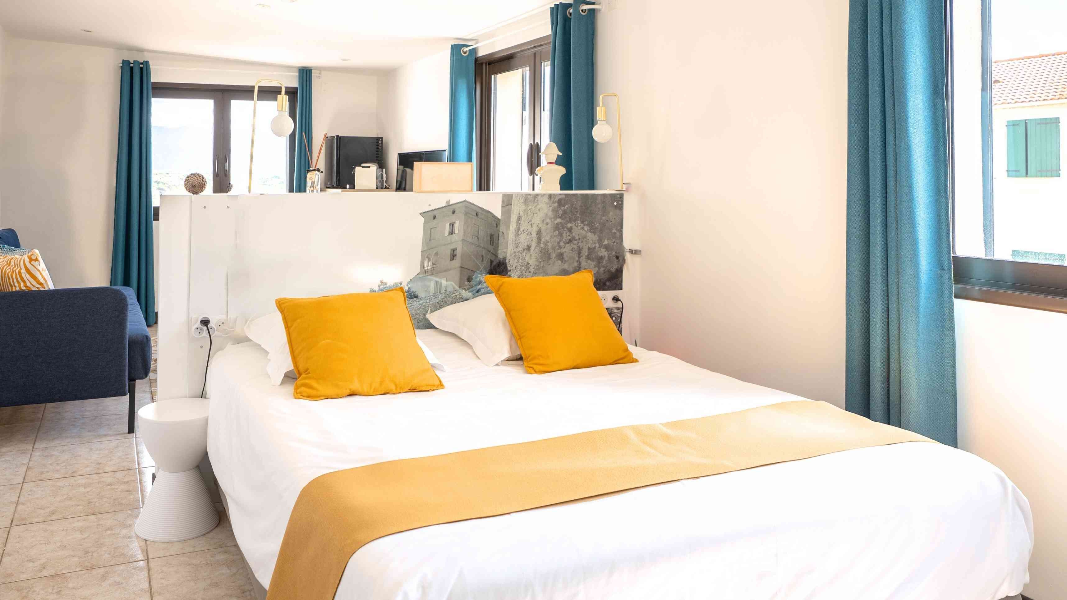 A hotel room with a bed, a bedside table, a chair, and a window with curtains.