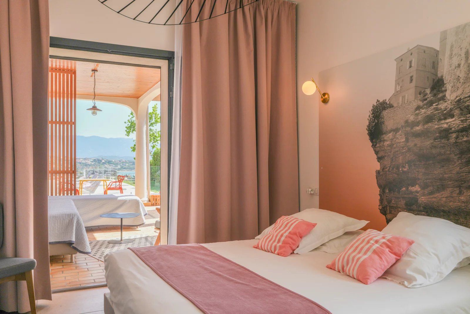 A bedroom with a bed, pillows, a nightstand, and a view of the outdoors.