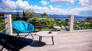 A balcony with a blue chair and a small table, overlooking a pool and mountains. - Casa Nova Maison d'hotes (Coggia)
