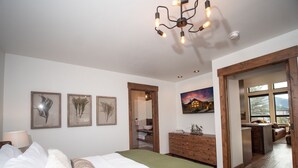 A bedroom with a bed, a dresser, a mirror, and a painting on the wall. - Chic Retreat – Indoor/Outdoor Fireplace, Private Jacuzzi, Great Location! (Estes Park)