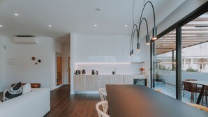 Een moderne keuken met witte kastjes, een houten eettafel en een bar.