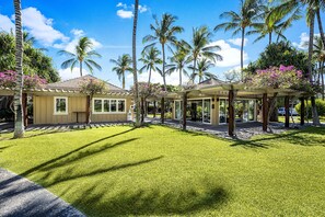 Ein Resort mit gepflegtem Rasen, Palmen und einem überdachten Außenbereich mit Glastür.
