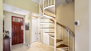 Un intérieur moderne avec un escalier en bois, des murs de couleur beige et une porte en bois.