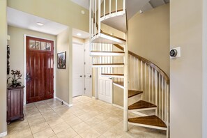 A modern interior with a wooden staircase, beige walls, and a wooden door.