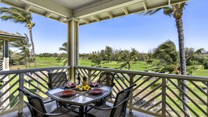 Un espace extérieur abrité, aménagé pour les repas, avec une table pour quatre personnes et une vue sur un terrain de golf.