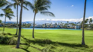 Un parcours de golf doté d’une piscine, de palmiers et offrant une vue sur un complexe hôtelier comprenant plusieurs bâtiments.