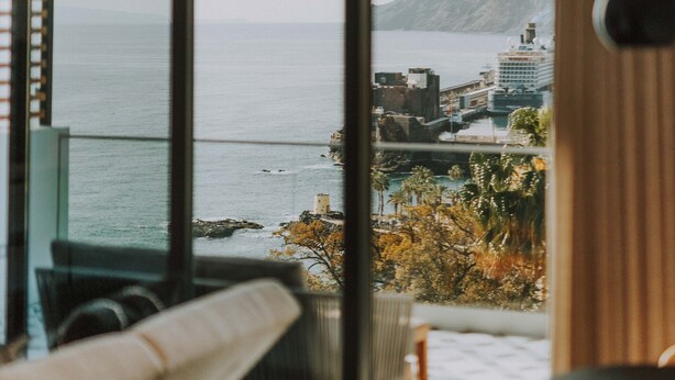 A modern room with a large sliding glass door leading to a balcony with a view of the sea and buildings. - FLH Casa Branca Madeira 301 (Funchal)
