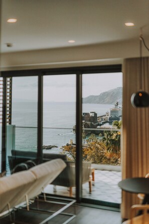 A modern room with a large sliding glass door leading to a balcony with a view of the sea and buildings. - FLH Casa Branca Madeira 301 (Funchal)