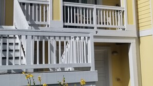 Un immeuble jaune à plusieurs étages, doté de balustrades blanches et d’un petit balcon.