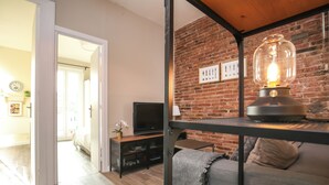 A modern living room with a brick wall, a sofa, a coffee table, and a television. - The Sants's balcony (Barcelona)