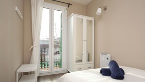 A bedroom with a bed, a wardrobe, a small table, and a radiator. - The Sants's balcony (Barcelona)