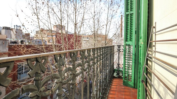 A balcony with a metal railing and a green door. - The Sants's balcony (Barcelona)