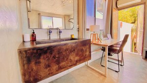 A modern bathroom with a large mirror, a sink with two faucets, and a wooden vanity.