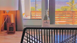 A hotel room with a view of mountains, a bottle of wine, a QR code, and a wooden chair.