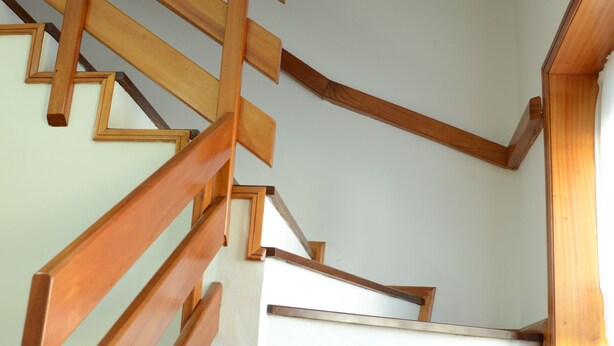 A wooden staircase with white walls and a framed picture on the landing.